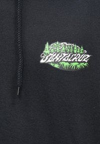 Țesătură neagră cu text grafic verde și alb "Santa Cruz" înconjurat de copaci stilizați verzi și frunze, alături de un șnur negru împletit.