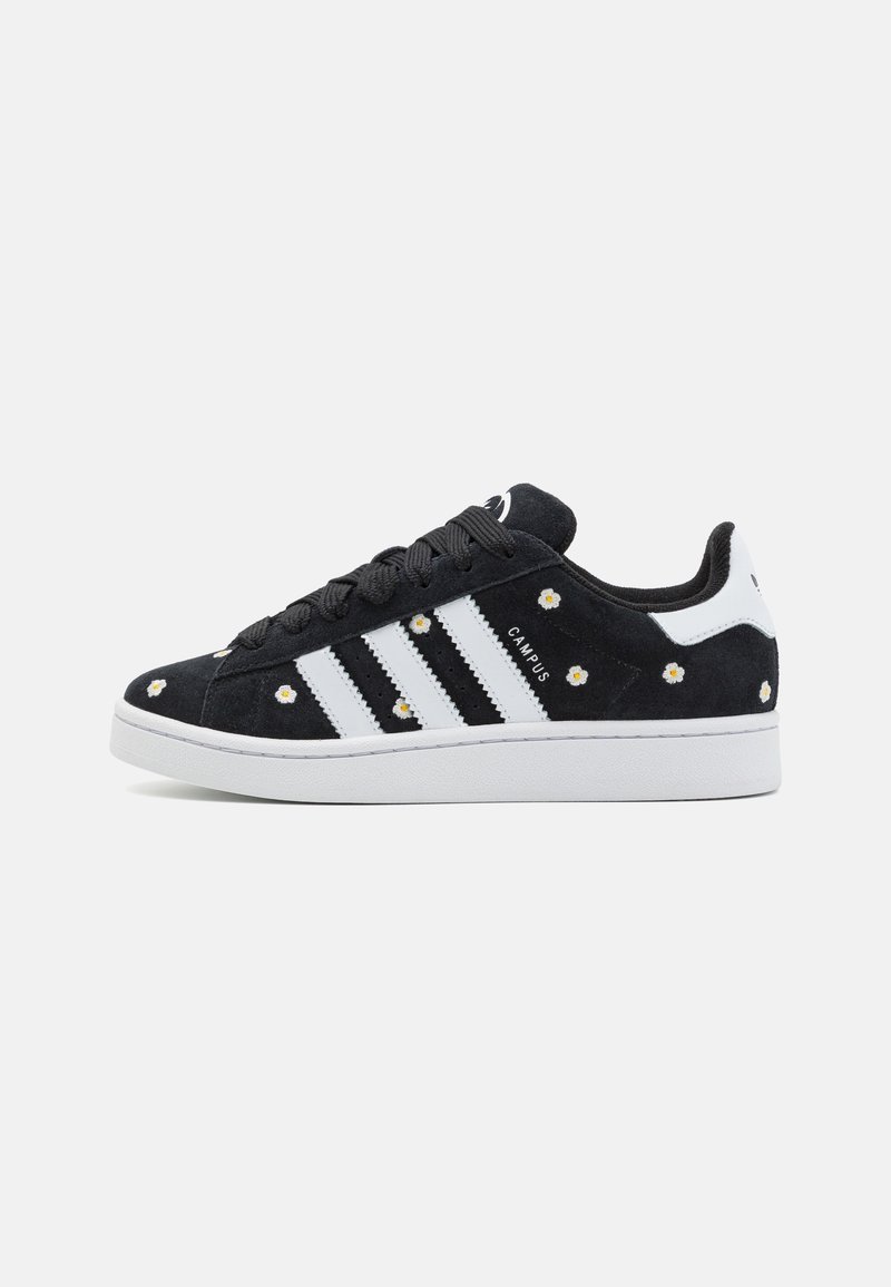 Baskets Adidas Campus noires avec rayures blanches, petits motifs de marguerites blanches et semelle blanche, présentées en profil latéral sur un fond blanc.