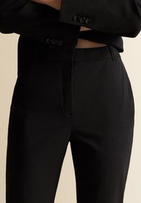 Mustat räätälöidyt housut, joissa on suora leikkaus, sileä pinta, etutaskut ja sävyyn sopivat napit vyötäröllä.