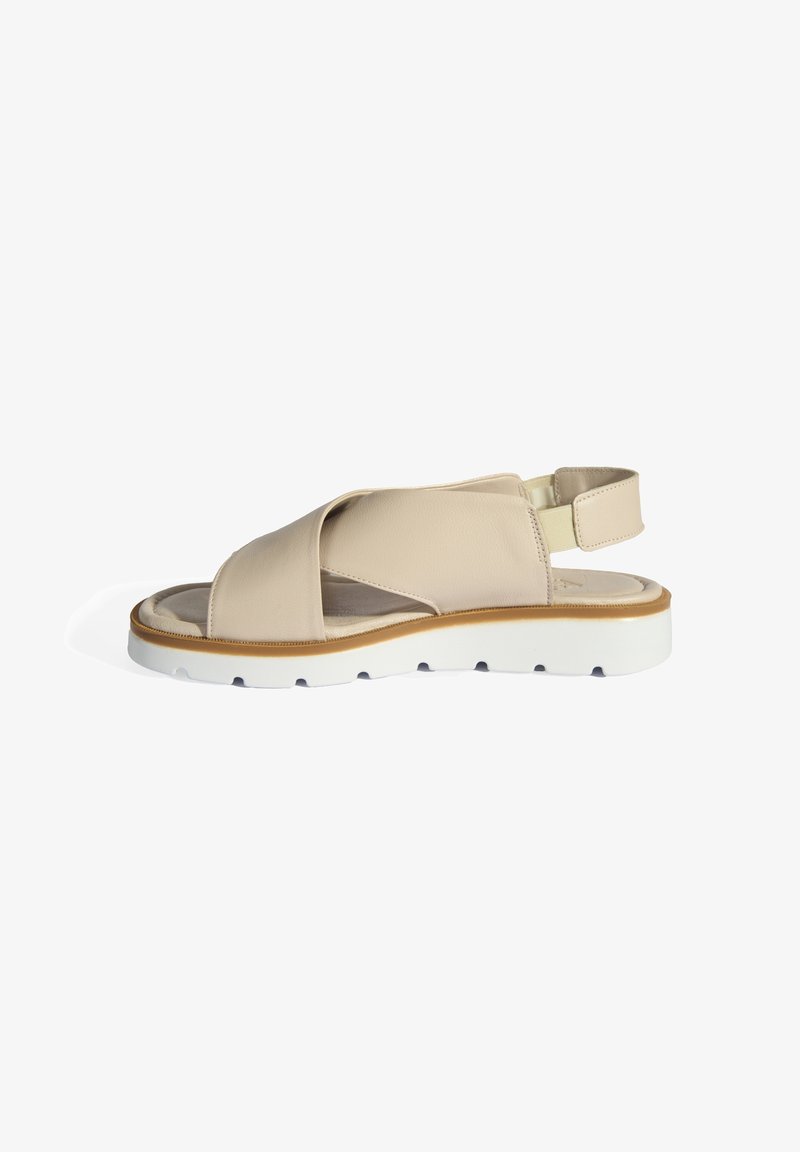 Sandale en cuir beige avec un design à bande croisée, une sangle de talon réglable et une semelle en caoutchouc blanche dotée d'un profil texturé pour une meilleure adhérence.