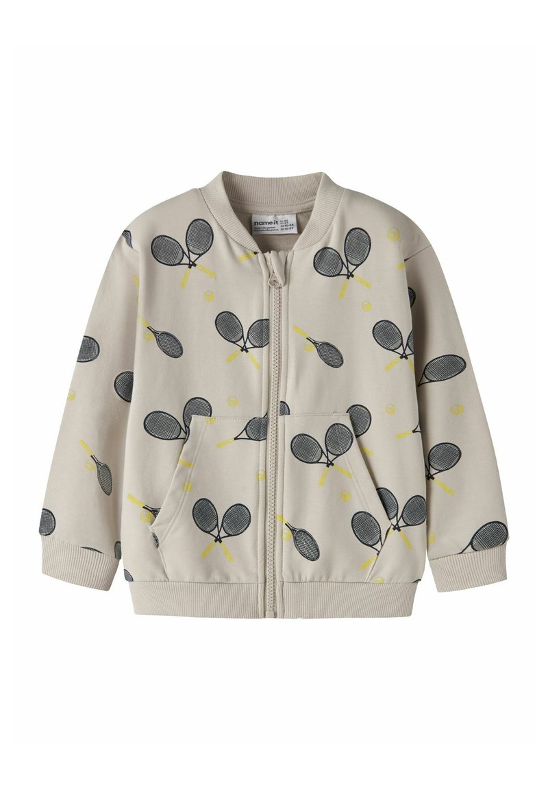 Hellbeige Reißverschlussjacke mit Tennis-Schläger- und Ballmuster in Schwarz und Gelb. Verfügt über gerippte Ärmelbündchen und Taschen, hergestellt aus weichem Material.