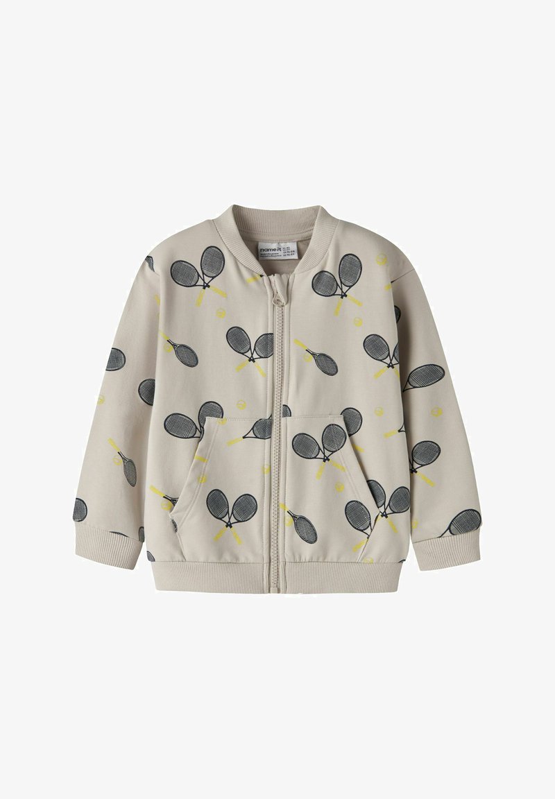 Hellbeige Reißverschlussjacke mit Tennis-Schläger- und Ballmuster in Schwarz und Gelb. Verfügt über gerippte Ärmelbündchen und Taschen, hergestellt aus weichem Material.