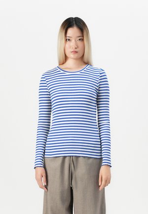 Maglietta a maniche lunghe a righe blu e bianche, realizzata in tessuto a coste. Presenta un collo a giro e un design aderente, abbinata a pantaloni beige.