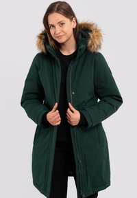 Parka verde con cappuccio in pelliccia sintetica removibile, chiusura con zip e tasche laterali. Presenta una texture liscia e un design della lunghezza del ginocchio.