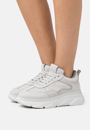 Baskets en daim gris avec une semelle blanche épaisse, dotées de lacets, d'un col rembourré et d'un marquage subtil sur les côtés et la languette.