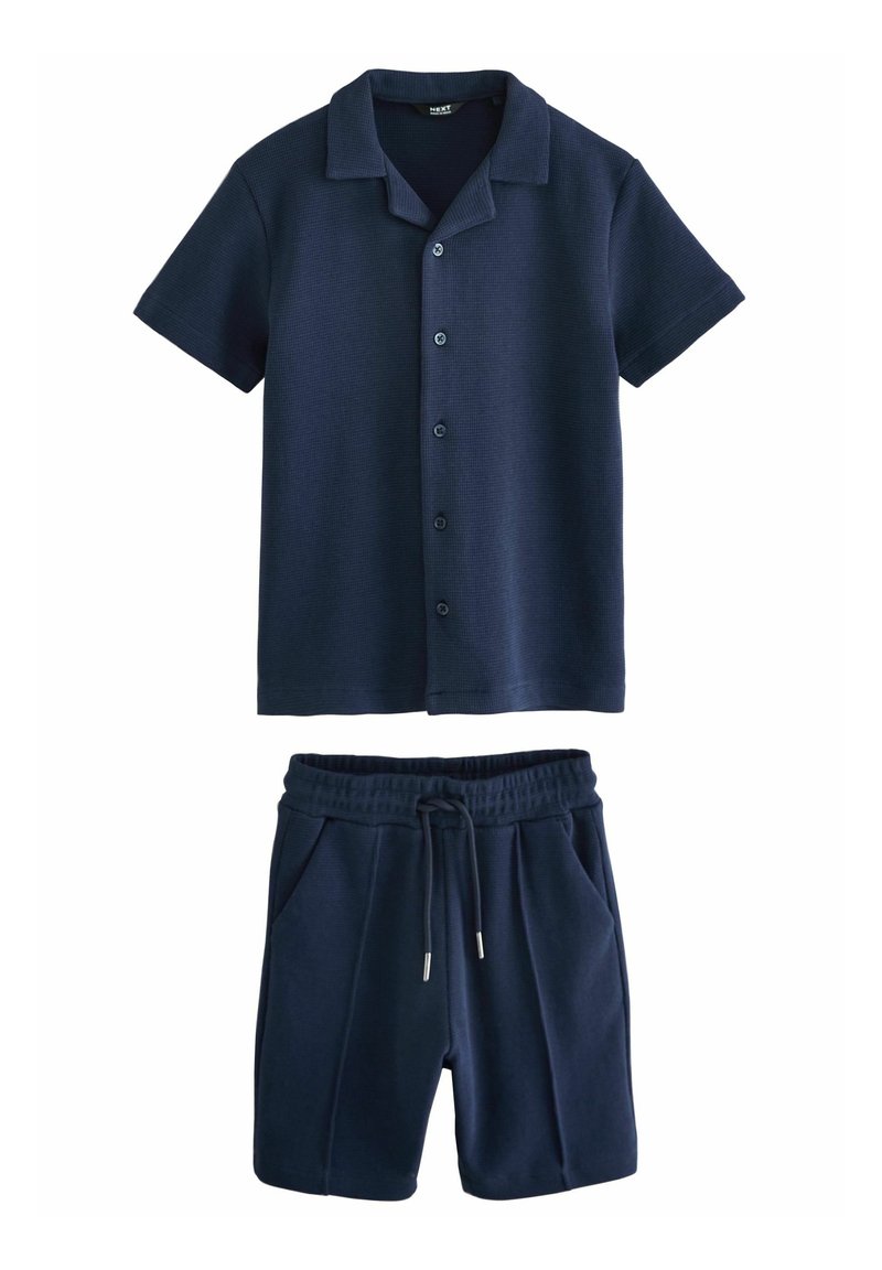 Chemise bleu marine à manches courtes avec boutons et col, associée à un short bleu marine à cordon avec poches.