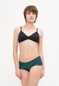 Black v-neck bralette with thin adjustable straps paired with green and blue patterned hipster shorts featuring a smooth fabric texture.
