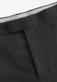 Schwarzer Stoff mit glatter Textur, ausgestattet mit einem flachen Bund, dezenten Nähten und einem grauen gemusterten Futter im Inneren.