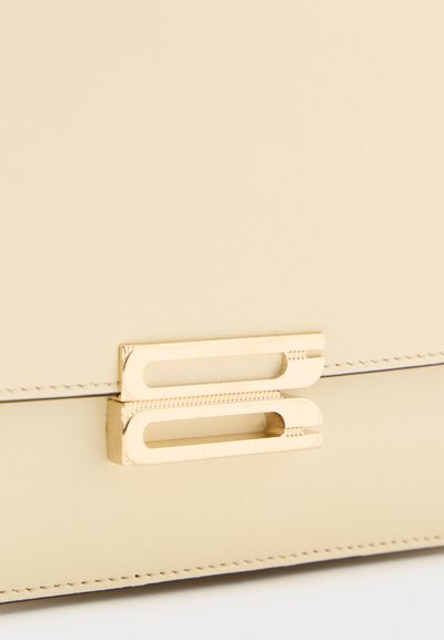 Cream leather bag with gold-toned rectangular clasp featuring two parallel hollow bars and stitched edges.