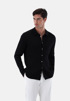 Schwarzes, geripptes Langarmshirt mit einem Button-down-Kragen, das weiße Knöpfe entlang der Knopfleiste und eine glatte Textur aufweist.