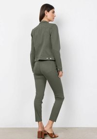 Olijfgroen jack en broek set in een getailleerd ontwerp, met een kraag, drukknoopsluiting en smalle pijpen, gecombineerd met bruine blokhak sandalen.