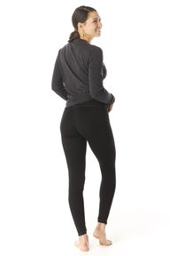 Black, form-fitting leggings with a smooth texture. Paired with a dark long-sleeve top, showing a relaxed fit and a round neckline.