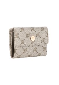 Cartera beige plegada con un patrón floral repetido y un broche circular dorado que presenta un emblema de flor en la solapa delantera.