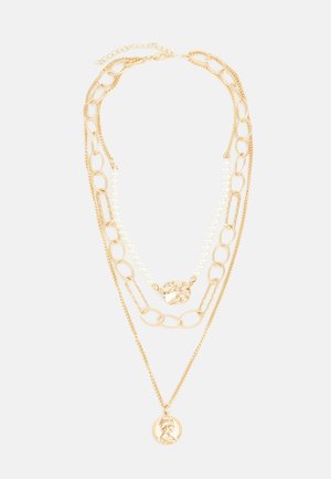 Kihtidega kuldne kaelakee, millel on keeratud lingid, pärlid ja detailne medaljon. Erinevad tekstuurid loovad visuaalset huvi.