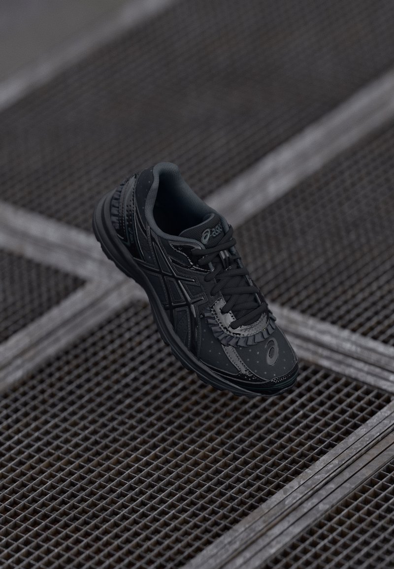 Baskets de sport noires au design épuré, avec une surface texturée, des lacets fins et des accents réfléchissants sur un revêtement à motifs.