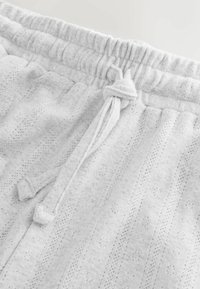 Lichtgrijze, gemêleerde sweatpants met een trekkoord in de taille, ribgebreide band en subtiele patroondetails door de stof.