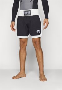 Svarte bokseshorts med hvite detaljer, elastisk midje og Venum-merke. Har en kobra-logo på venstre bein.