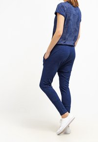 Modrý krátký rukáv top a odpovídající jogger kalhoty vyrobené z měkké látky. Top má texturovaný design; kalhoty mají boční kapsy a slim fit.