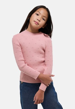 Pull à col rond en tricot côtelé rose avec des détails en billes texturées, manches longues. Associé à un jean en denim bleu.