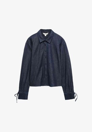 Ciemnoniebieska, długi rękaw, koszula jeansowa na guziki z kołnierzykiem i troczkami przy mankietach, rozłożona na płasko na białym tle.