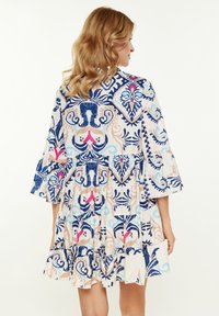 Abito con motivo floreale e maniche a campana, caratterizzato da colori blu, rosa e beige in un design a più strati e realizzato in tessuto leggero.