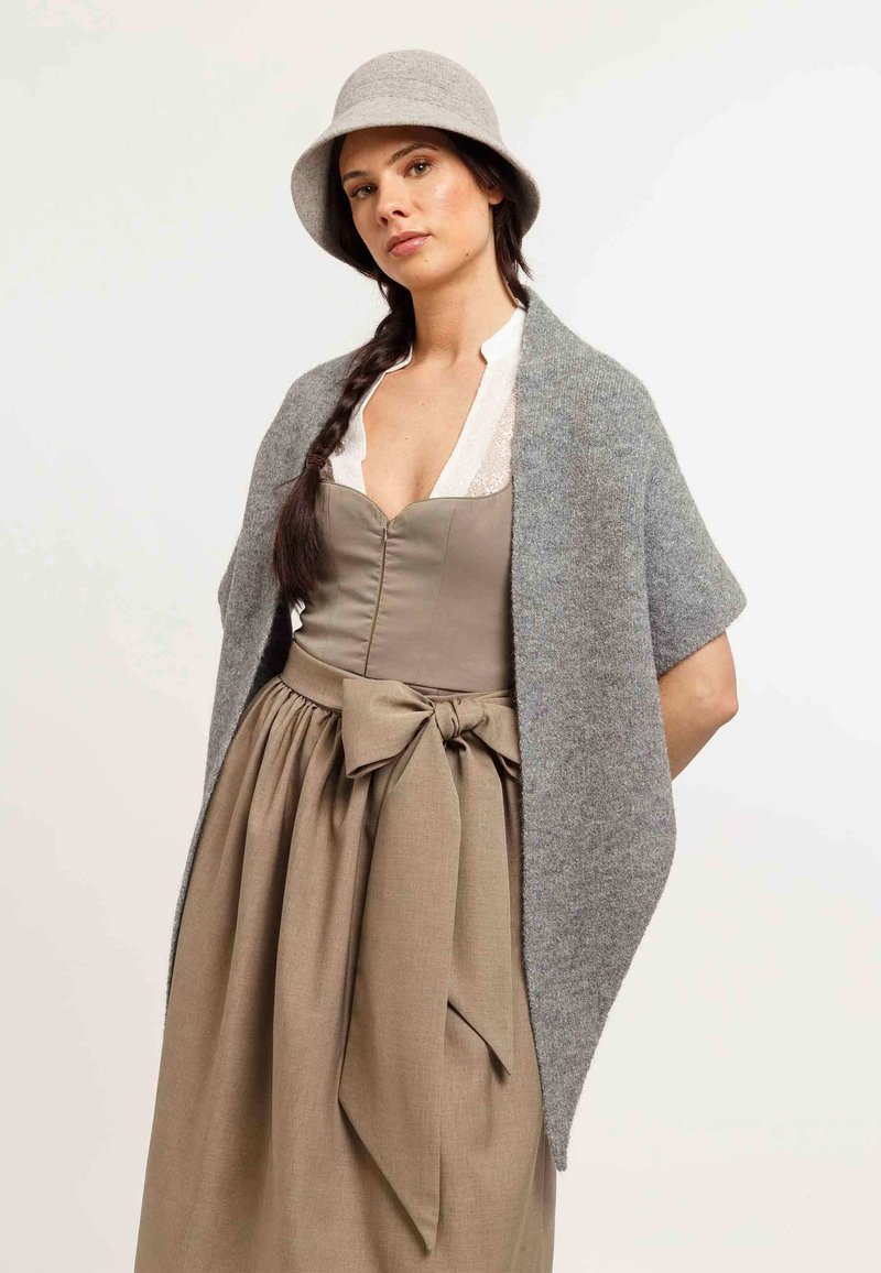 Șal gri din lână așezat peste o rochie bej cu o fundă în talie. Modelul poartă o pălărie din fetru gri și o bluză din dantelă albă.