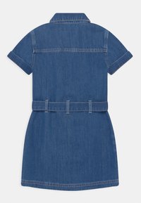 Vista trasera de un vestido de mezclilla de mangas cortas con cuello y pasadores para cinturón, que presenta un lavado azul medio y mangas arremangadas.