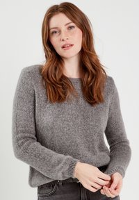 Suéter gris de punto con una textura suave, cuello redondo y mangas largas. Cuenta con puños acanalados y un corte relajado.