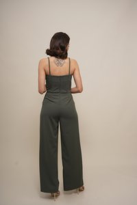 Mono verde oliva con tirantes finos, cuerpo ajustado y pantalones de pierna ancha. Tela suave con un ligero brillo; cierre de cremallera en la parte posterior.