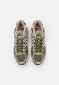 Baskets de sport vertes et grises avec une tige en maille, pointe arrondie et semelle en caoutchouc ; elles présentent trois rayures blanches et des accents beige contrastants.
