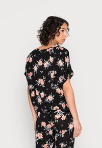Blusa preta de flores com mangas curtas, apresentando um padrão vibrante de rosas em tons de rosa e azul, tecido leve e um design de corte solto.