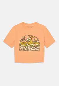 Korte mouw, cropped t-shirt in perzik, met een multikleurige grafische print van bergen, golven en een zon. Gemaakt van zachte stof.
