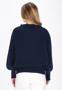 Maglione lavorato a maglia blu navy con un design testurizzato, maniche ampie e orlo a costine. La vista posteriore mostra un collo rotondo e una vestibilità comoda.