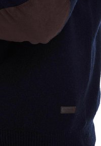 Kapuzenpullover aus navyblauer Wolle mit braunen Wildleder-Patches an den Ellbogen, gerippten Bündchen und einem kleinen gebrandeten Lederschild am unteren Vorderteil.