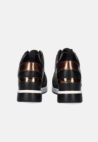 Zapatillas negras con una parte superior de tela texturizada, acentos metálicos en bronce y una suela blanca gruesa. Presentan un tacón pronunciado y una lengüeta de agarre.