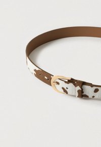 Καφέ και λευκή ζώνη με στίγματα από μαλακό υλικό με πόρπη από μεταλλικό υλικό σε χρυσαφί τόνο. Έχει απαλό υφή και πολλαπλές τρύπες ρύθμισης.