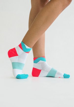 Bunte Sportsocken mit einem geometrischen Muster, das weiße, türkisfarbene und pinke Abschnitte zeigt. Knöchellanges Design mit kontrastierendem Zehenbereich.