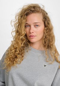 Felpa grigia con scollatura rotonda, tessuto morbido e maniche lunghe. Caratterizzata da un piccolo logo nero ricamato sul petto.