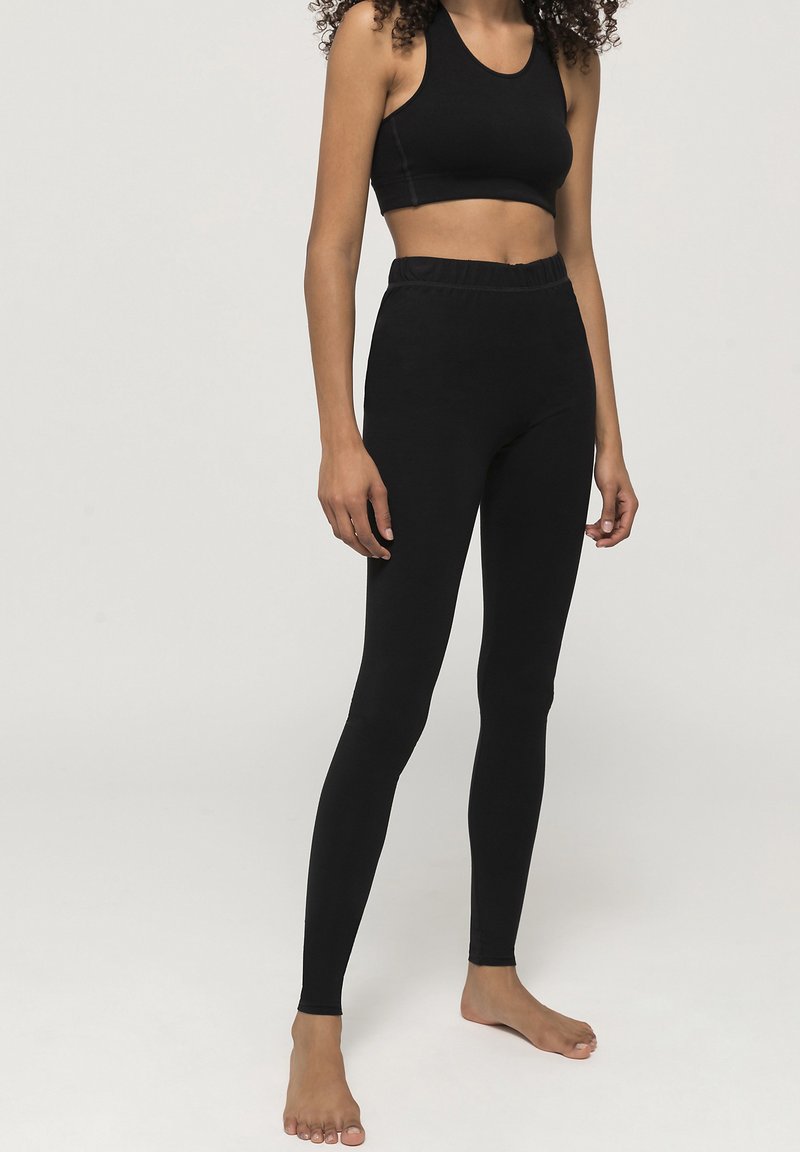 Zwarte sportoutfit bestaande uit een strakke crop top en hooggekapte legging, gemaakt van een rekbaar materiaal met een gladde textuur.