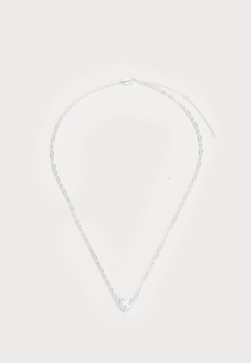 Collar de cadena de plata que presenta una gema clara en forma de corazón en el centro, con eslabones ovalados y un cierre de langosta seguro.