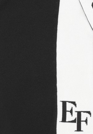 Tela de punto en blanco y negro presenta un diseño vertical con un destacado logotipo "EF" en negro sobre la sección blanca, enfatizando el contraste.