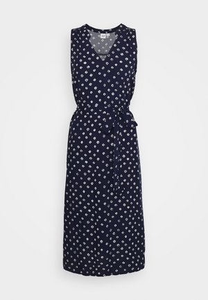 Sleeveless navy blue midi dress with white geometric dots, V-neckline, and matching fabric belt tied at the waist.