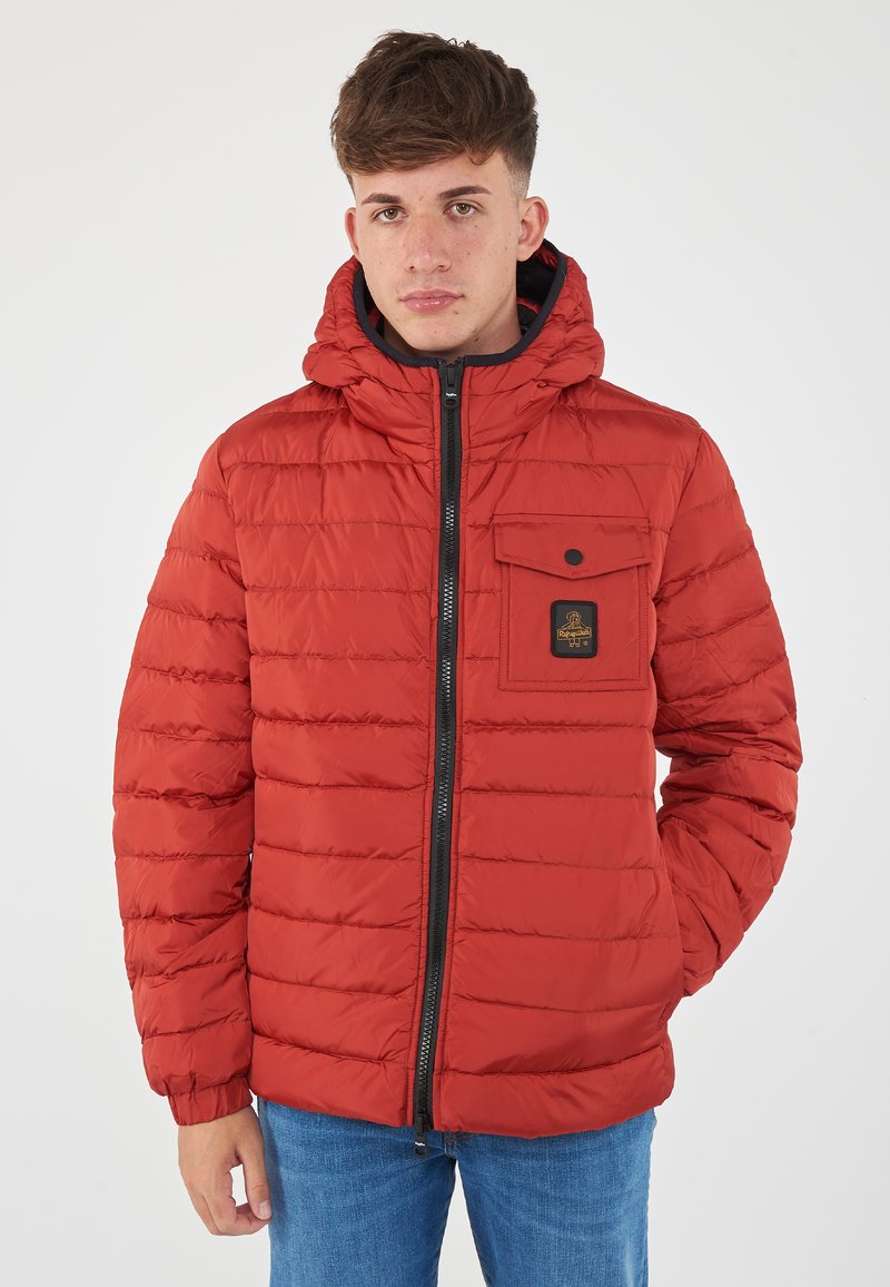 Giacca a vento rossa con design trapuntato orizzontale, chiusura con zip e cappuccio fissato. Presenta una tasca frontale con chiusura a scatto e logo.
