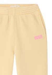 Pantaloni sportivi gialli in tessuto morbido, con fascia in vita a coste, tasche laterali e logo rosa "AMERICAN VINTAGE".