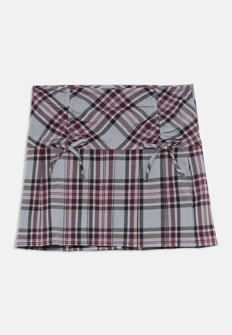 Jupe mini à carreaux gris et bordeaux avec des plis et deux petits nœuds attachés à l'avant de la taille sur fond blanc.