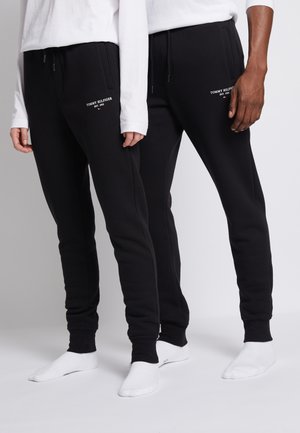 Sorte sweatpants med elastiske manchetter og snor i taljen. Har "Tommy Hilfiger EST. 1985" logo i hvidt på venstre lår.