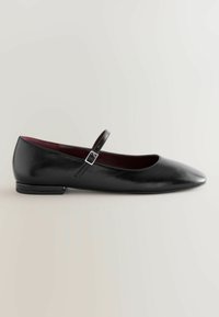 Black leather flat Mary Jane shoe with a small heel and an adjustable buckle strap across the instep.