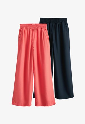 Két pár bőszárú nadrág rugalmas derékpánttal és oldalzsebekkel, egyik korallrózsaszín, a másik sötét tengerészkék, egymás mellett kiállítva.