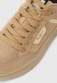 Μπεζ σουέτ αθλητικό παπο�ύτσι με στρογγυλεμένη μύτη, επίπεδους κορδόνια, διάτρητο πλάι και υφασμένο μεσαίο μέρος. Διαθέτει λογότυπο στο πλάι και μαλακή υφασμάτινη επένδυση.