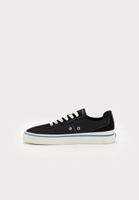 Black canvas sneaker with white laces, white sole, and blue accent stripe. Features a rounded toe and two circular vent holes on the side.